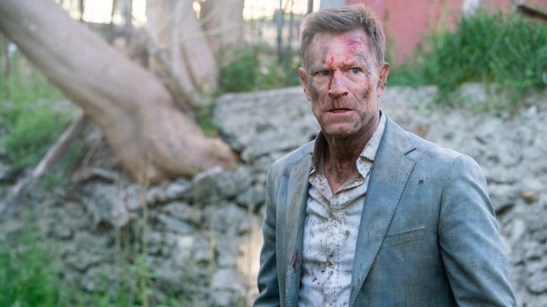 Vail grimaces, covered in blood in "The Bricklayer" (2023)