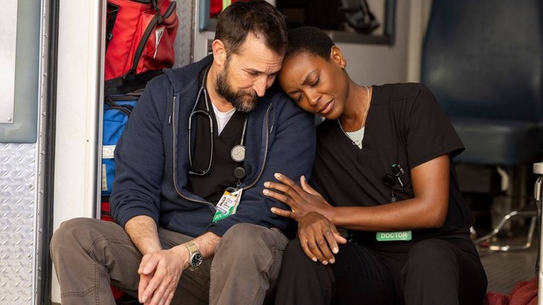 Robby (Noah Wyle) comforting his friend, colleague, and ex-girlfriend, Heather (Tracy Ifeachor) in the back of a vacant ambulance on "The Pitt"