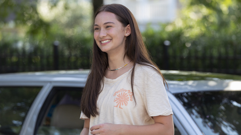 Belly smiling in front of a car in "The Summer I Turned Pretty" Season 1.
