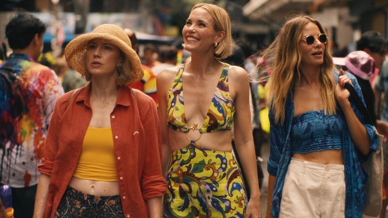 Old friends Laurie (Carrie Coon), Kate (Leslie Bibb), and Jaclyn (Michelle Monaghan) walking down a busy street in Thailand on "The White Lotus" Season 3