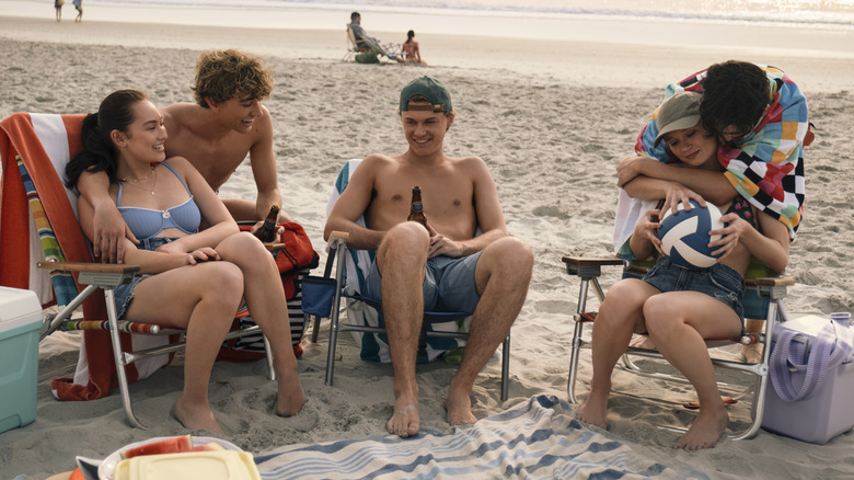 Belly, Jeremiah, Conrad, Taylor, and Steven sitting on the beach in "The Summer I Turned Pretty" Season 3.