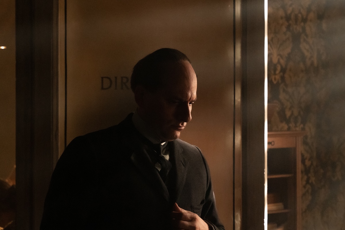 Luca Marinelli in 'Mussolini: Son of the Century,' shown standing in the doorway, a dark shadow over his face