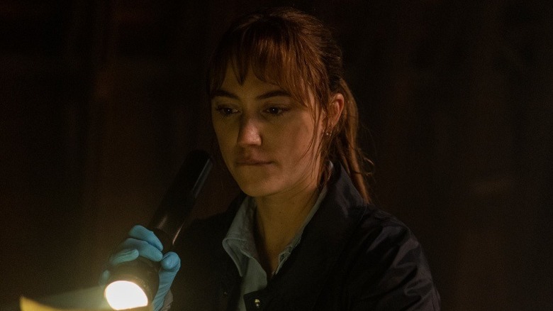 Lee holding a flashlight to a piece of paper in "Longlegs" (2024)