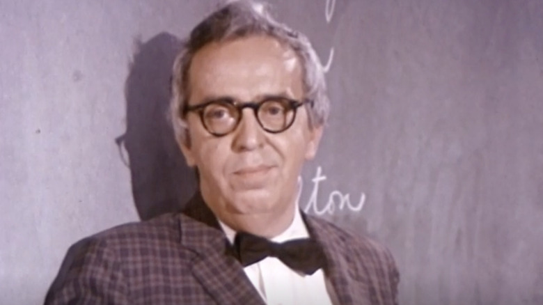 Kenneth Dragen stands against a black chalkboard