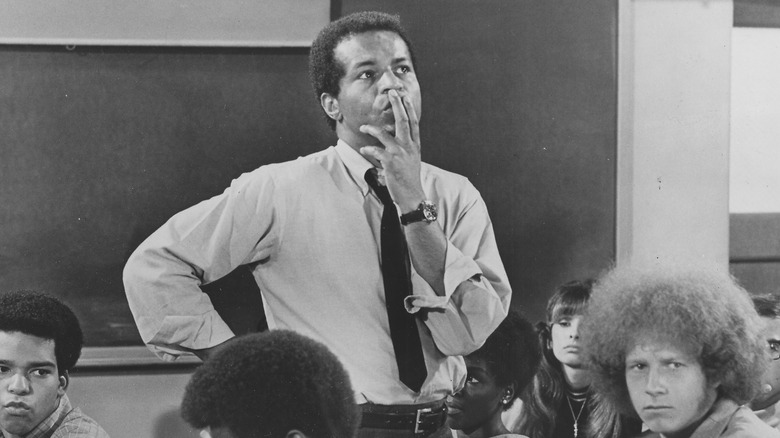 Pete Dixon holds a hand to his mouth in his classroom