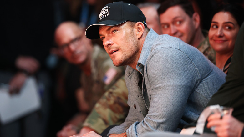 Alan Ritchson leans forward in a chair