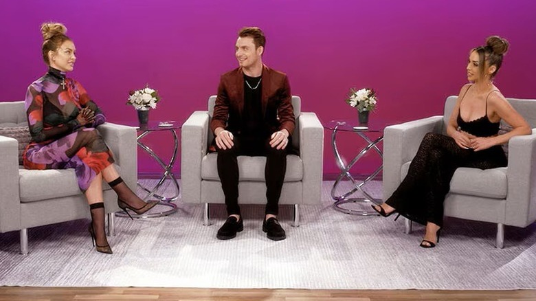 Three people sitting on gray chairs in front of a pink wall on "Vanderpump Rules After Show" (2015-present)